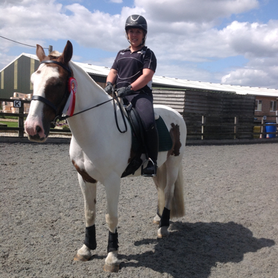Horse and rider with online dressage rosette standing in arena