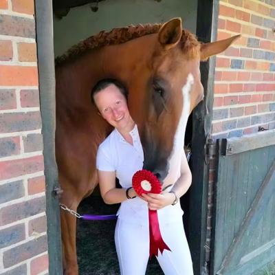 Horse and rider stood in a stable door with a red rosette